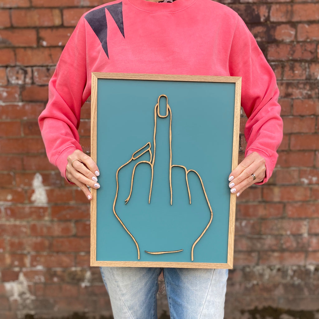 turquoise hand painted wooden sign with wooden middle finger gesture on top