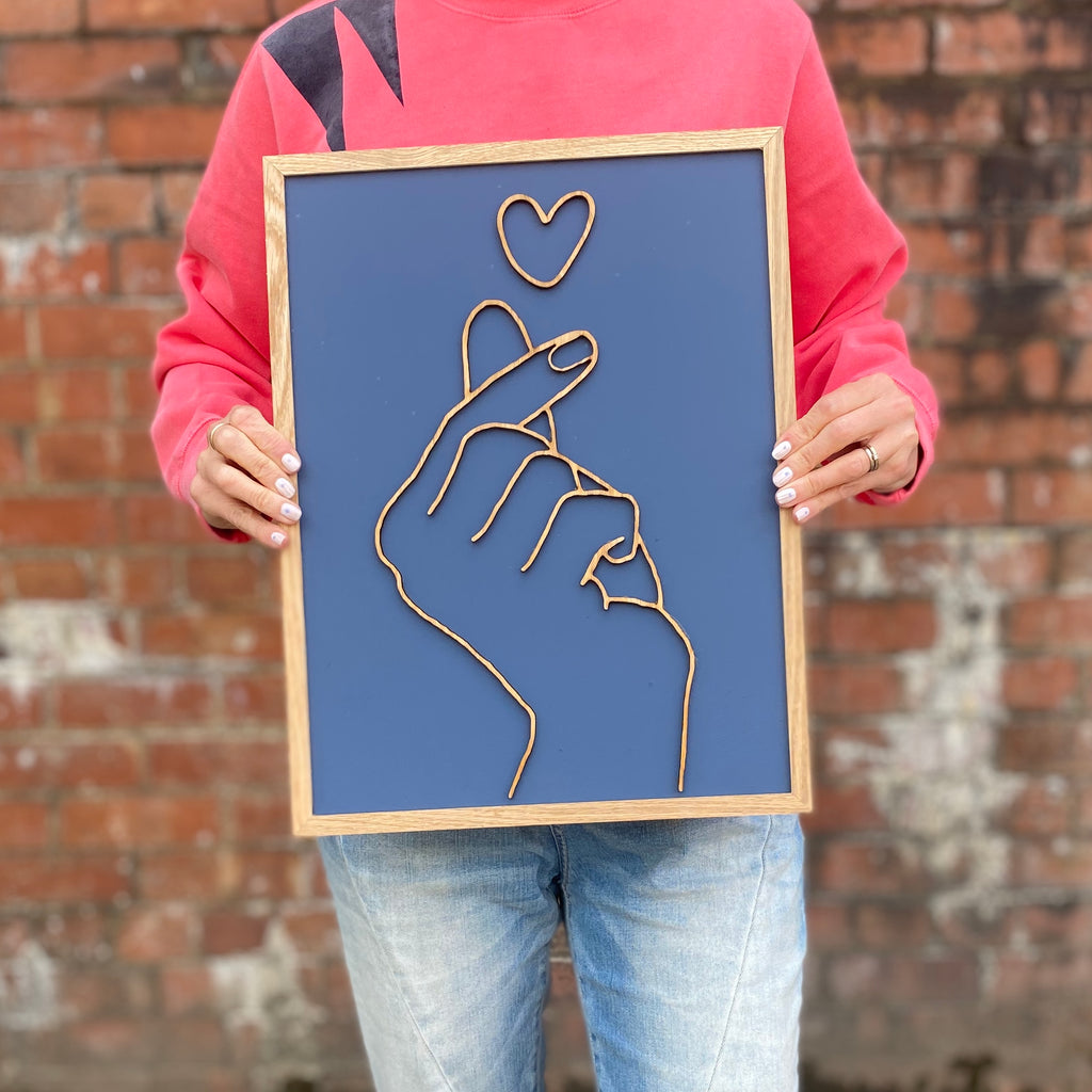 hand painted blue wooden sign with love hand gesture on top