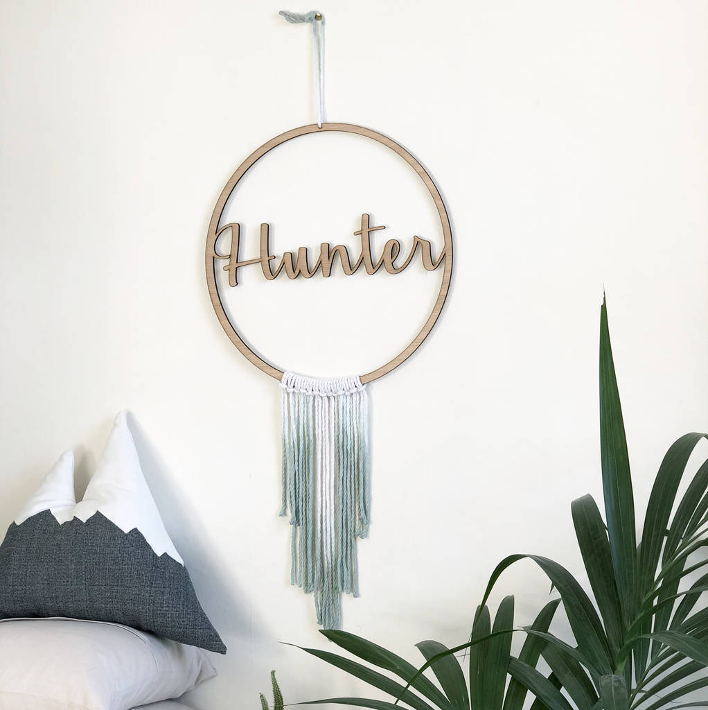 wooden circular sign with word in the middle. green dyed string creating a gradient fade makes the sign resemble a dream catcher. 