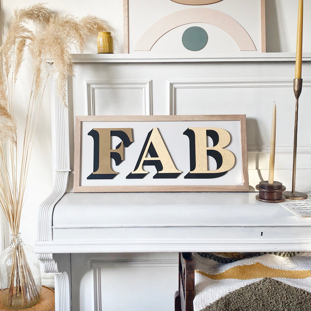One word painted sign placed upon piano and displaying the word 'Fab' in gold