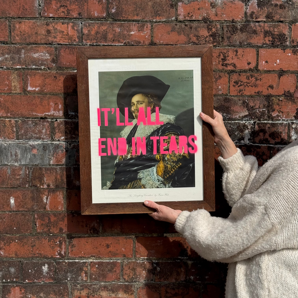 Person holding a framed picture with text against a brick wall