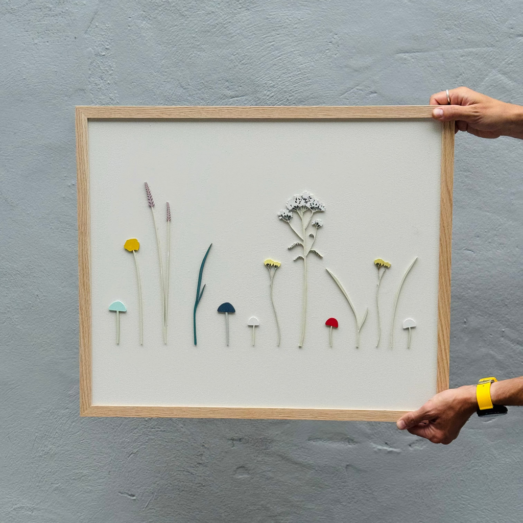 Framed artwork with small flowers on a gray wall