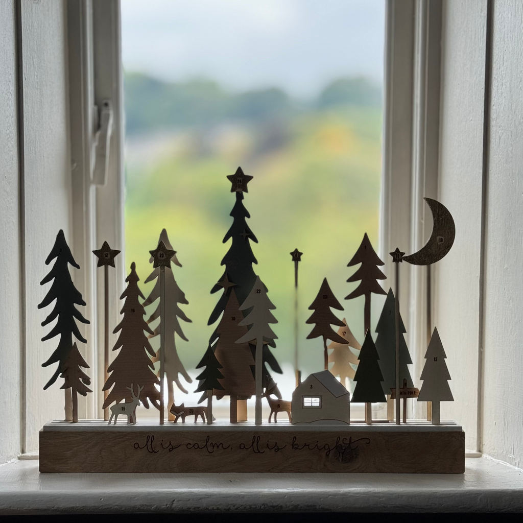 Decorative wooden sculpture with cut-out trees and animals on a windowsill.