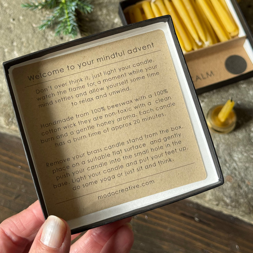 Hand holding a card with instructions for candles, with candles and packaging in the background.