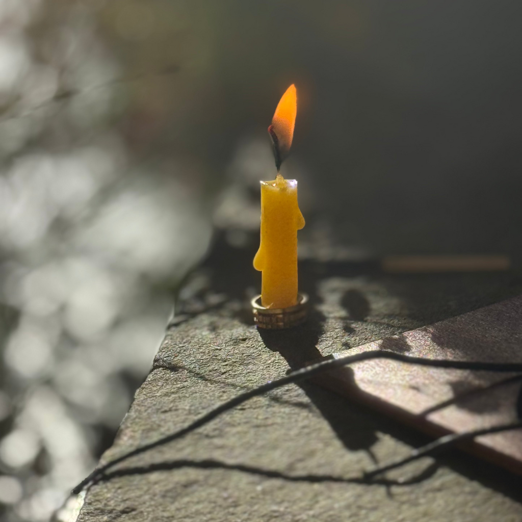 beeswax candle burning in the winter sun on a stone shelf