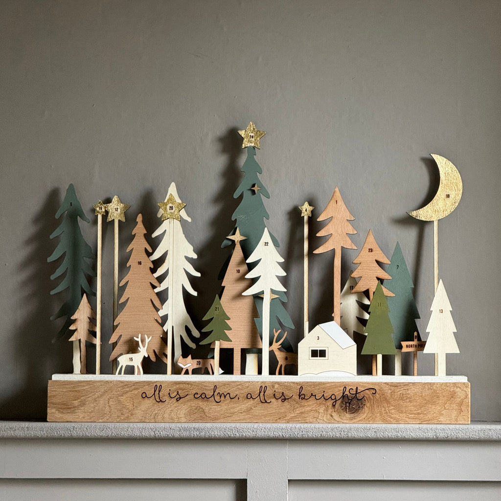 Wooden decorative scene with trees and a moon on a gray surface