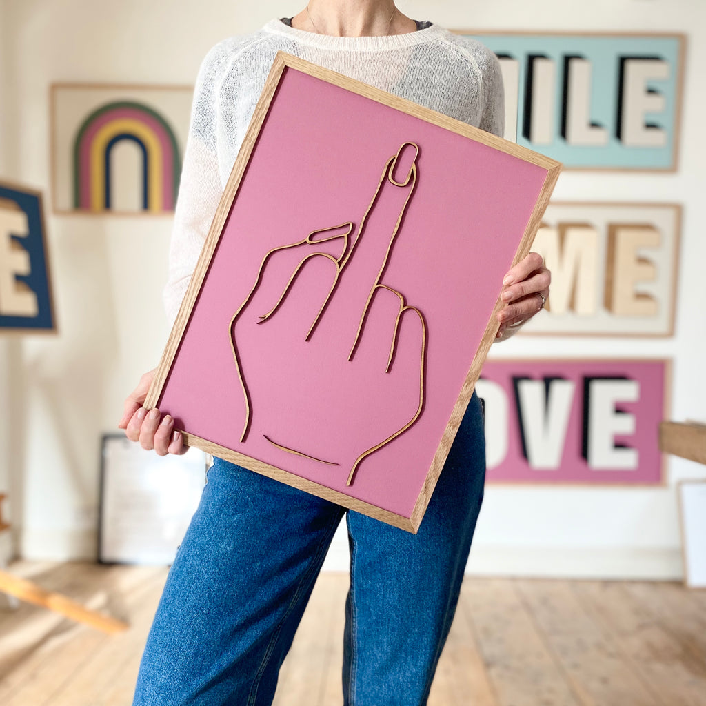 pink sign with wooden middle finger hand gesture over the top. person for perspective