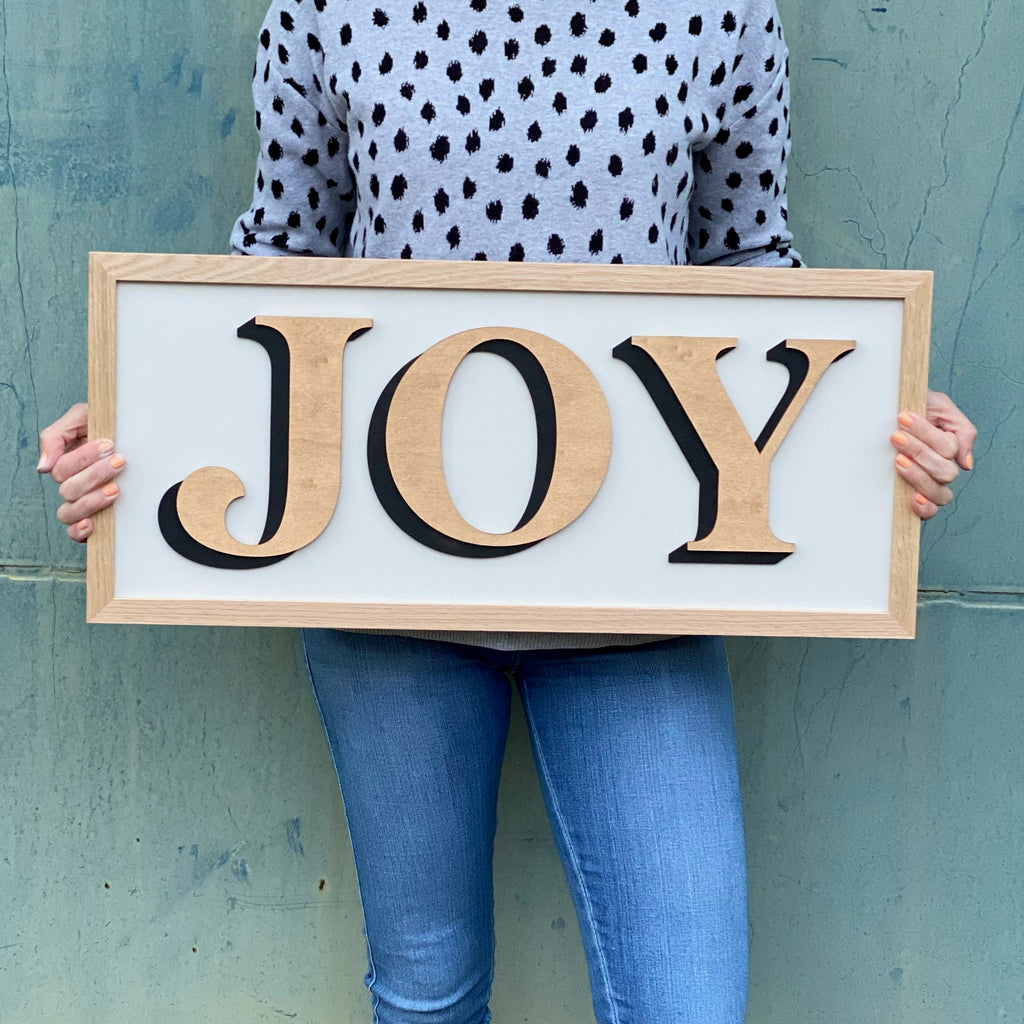 One word painted sign displaying the word 'Joy' in gold