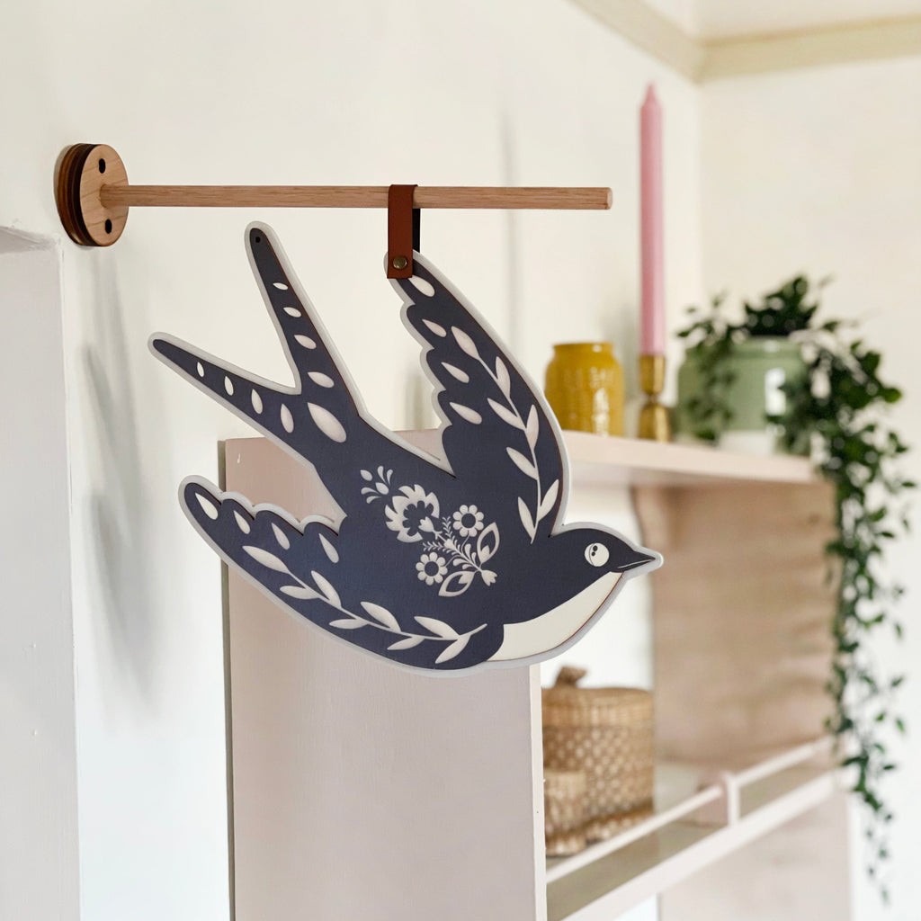 Patterned bird hanging displayed on wall.