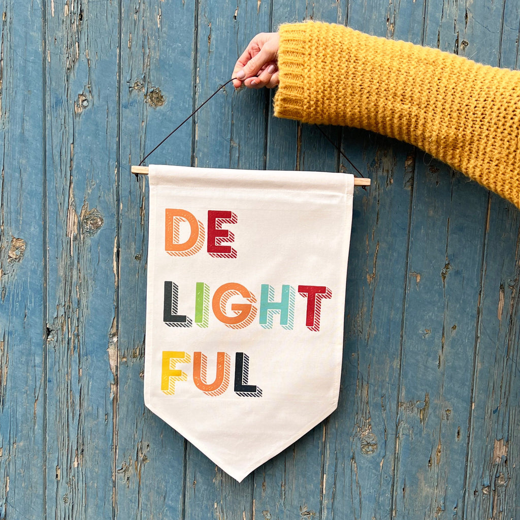 Vibrant fabric wall hanging displaying the word 'Delightful' against textured wall