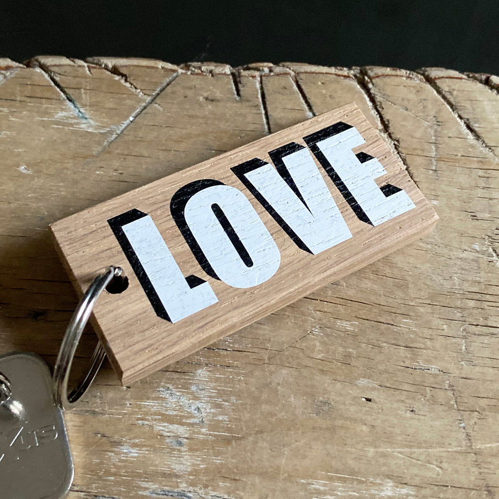 Keyring reading 'love' in white lettering with black drop shadow.