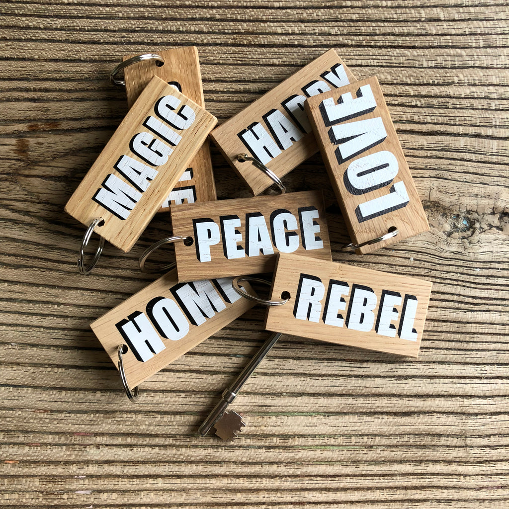 large selection of wooden keyring displaying single words with white lettering and black drop shadow
