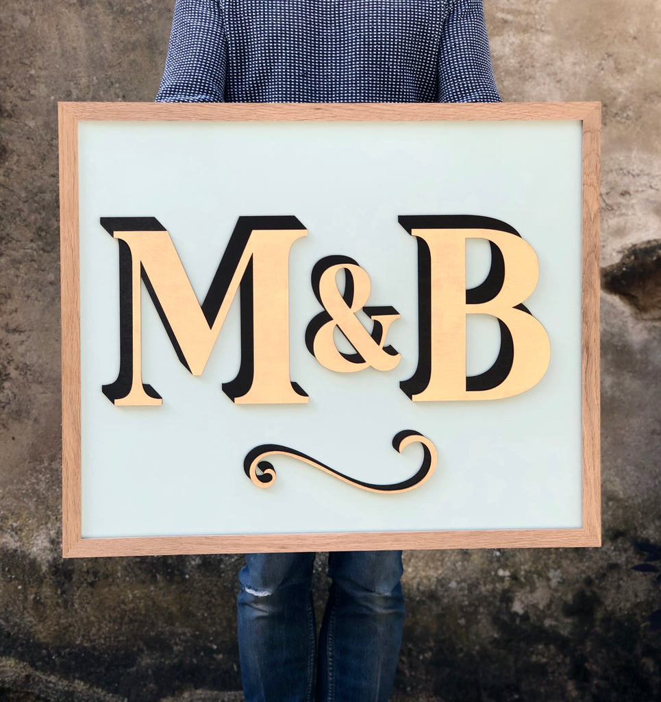 Personalised sign displaying the initials M&B. Displayed by person holding