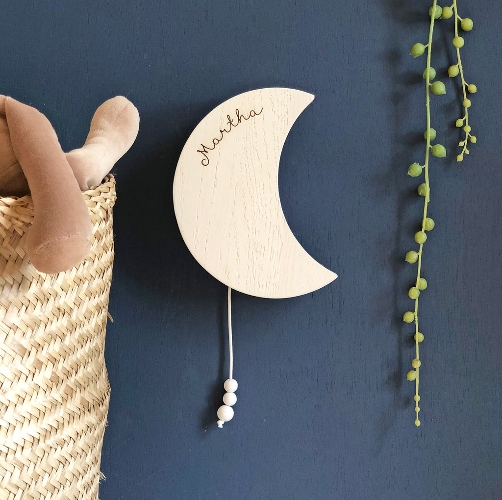 crescent moon shaped wooden, musical wall hanging in white displaying the word 'Martha'