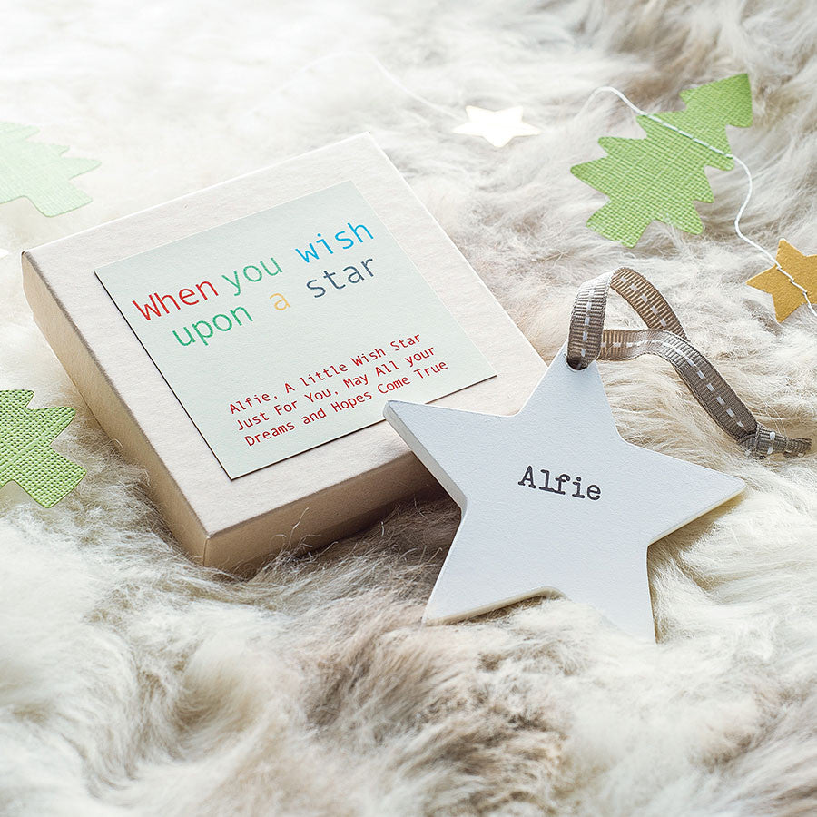 white wooden star with ink printed lettering and grey thread to hang from