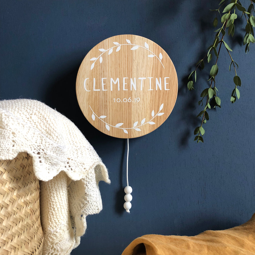 Circular wooden, music hanging displaying the word 'Clementine' in white.